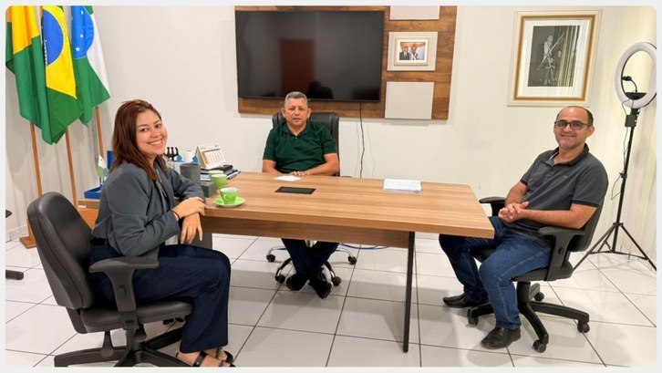 Justiça Eleitoral intensifica mobilização por biometria em Marechal Thaumaturgo Três pessoas estão sentadas em uma sala de reuniões, em volta de uma mesa retangular de madeira....