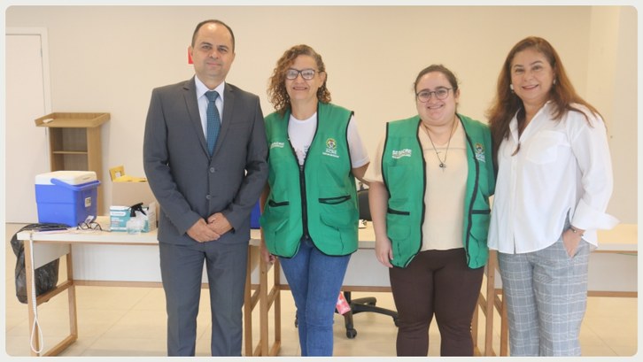 TRE-AC realiza ação de vacinação para servidores e familiares com parceria da Sesacre Cinco pessoas estão em pé, lado a lado, sorrindo para a foto em um ambiente interno bem iluminad...